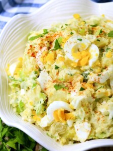 Classic Potato Salad with chopped eggs in a white bowl with napkin
