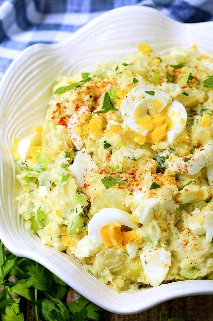 potato Salad with chopped eggs in a white bowl with napkin