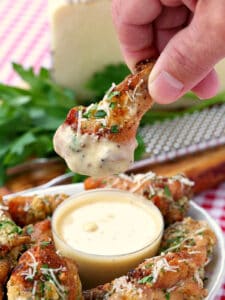 chicken wing dipping into garlic parmesan sauce