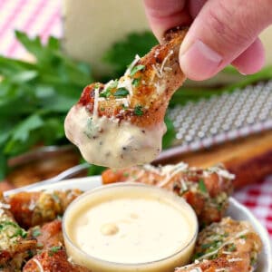 chicken wing dipping into garlic parmesan sauce