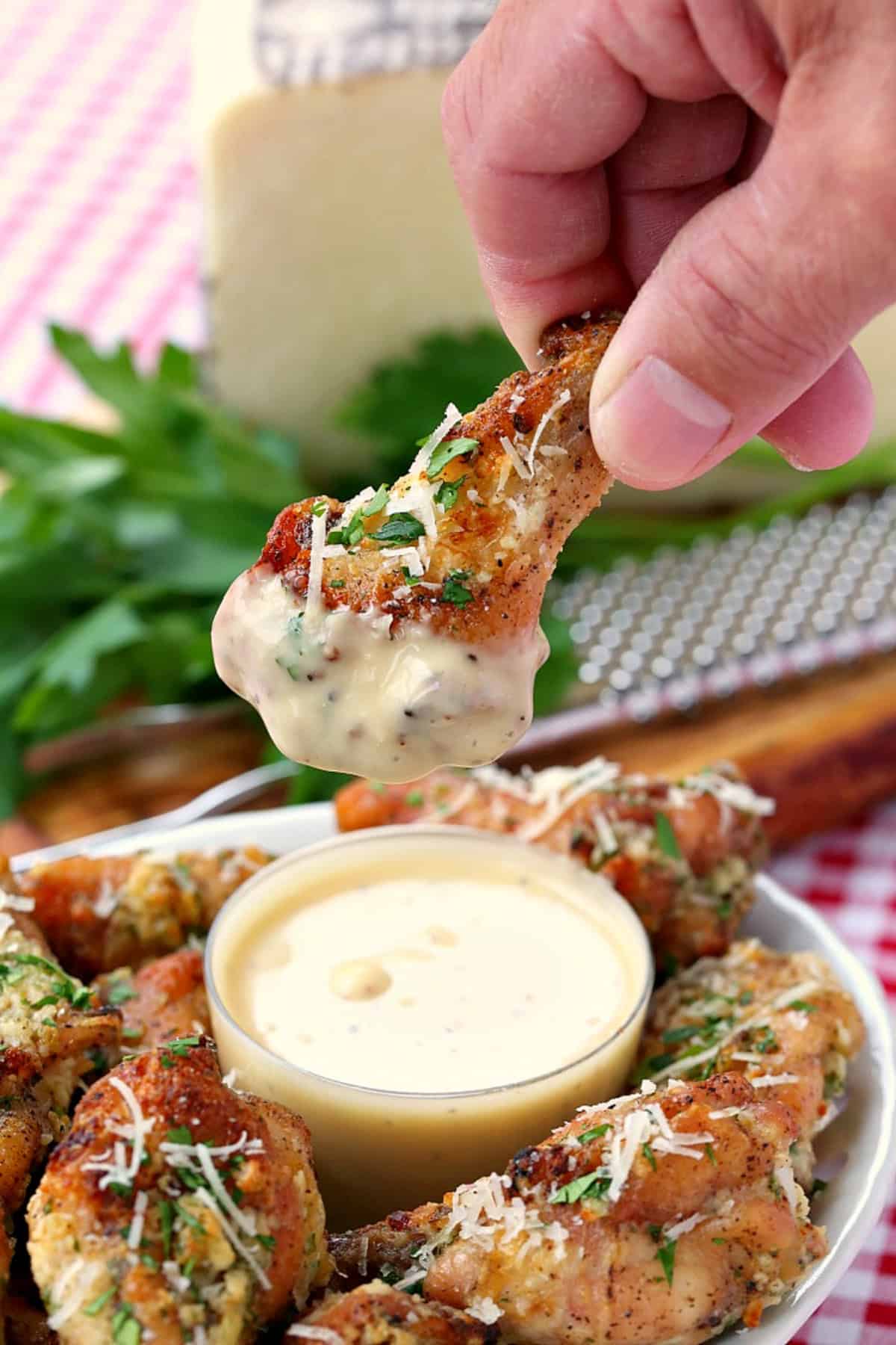 chicken wing dipping into garlic parmesan sauce