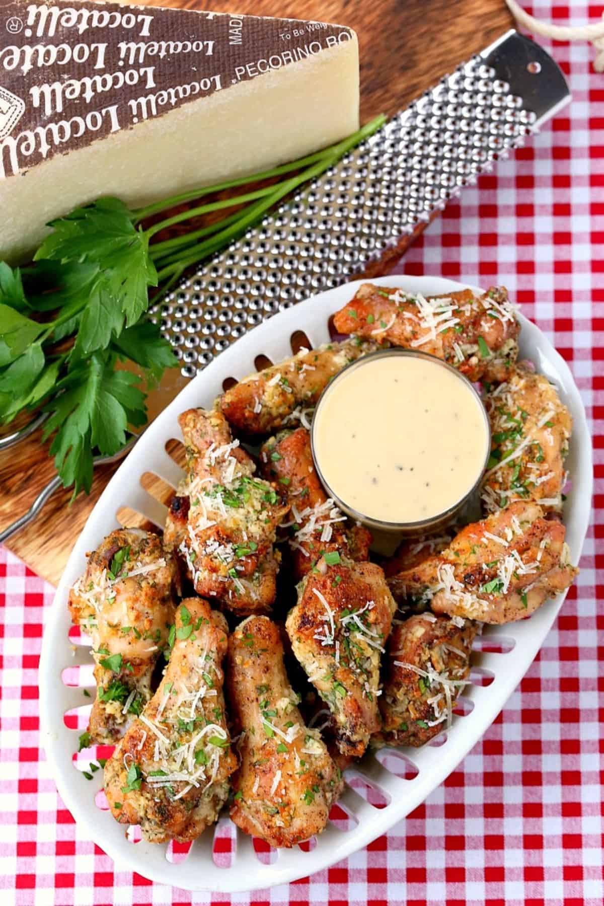 chicken wings on a platter with parmesan cheese on the side