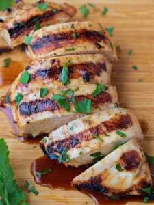 sliced grilled chicken breast on a board