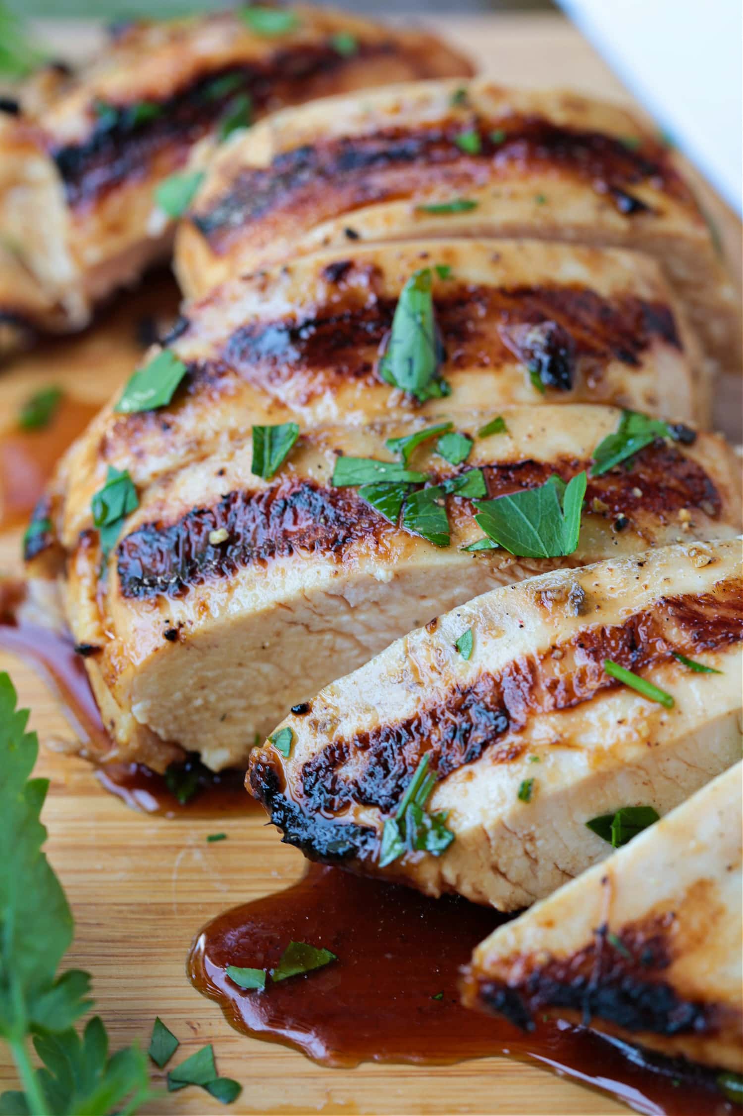 sliced, grilled chicken breast on board with juice