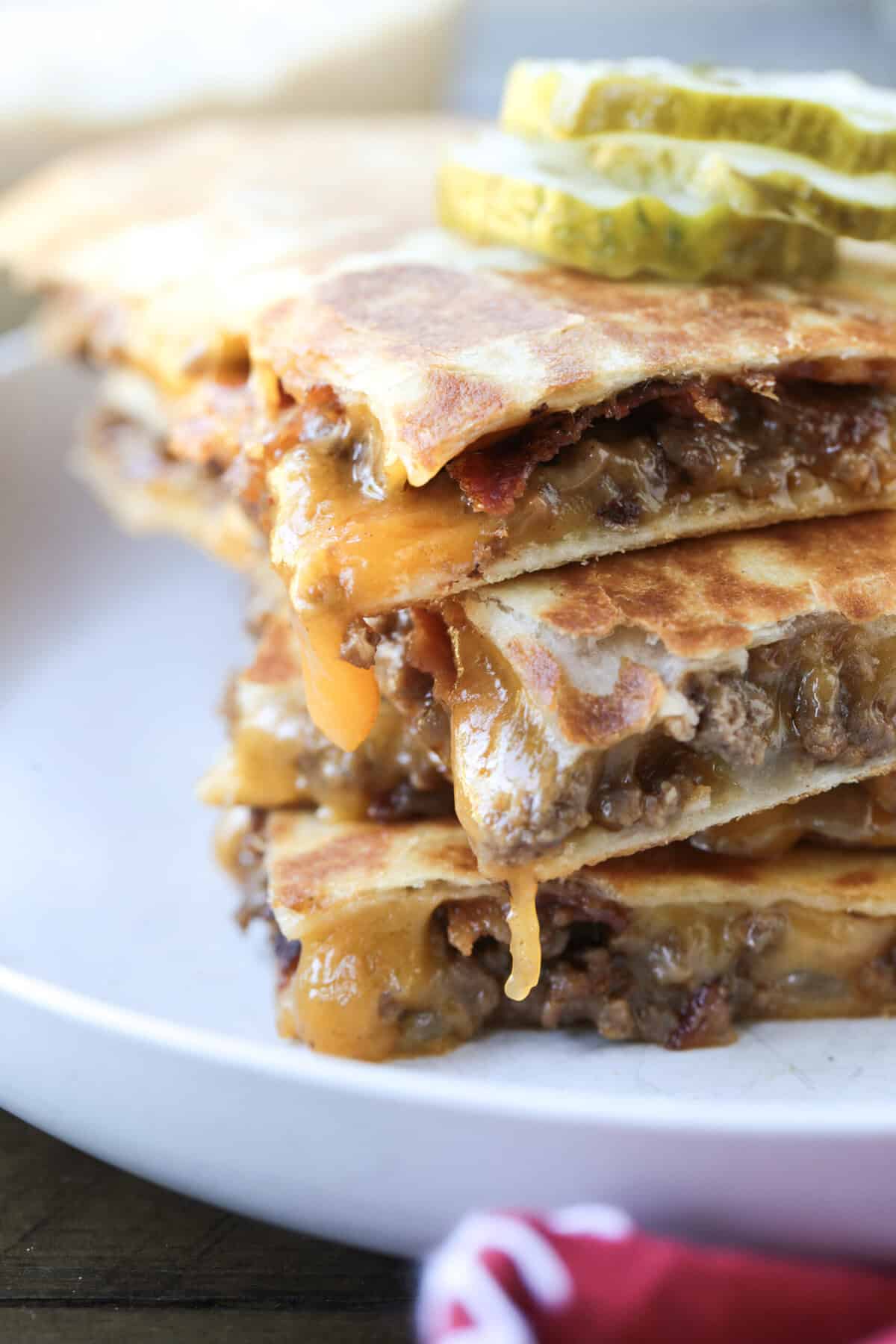 quesadillas stacked on a plate with pickles on top