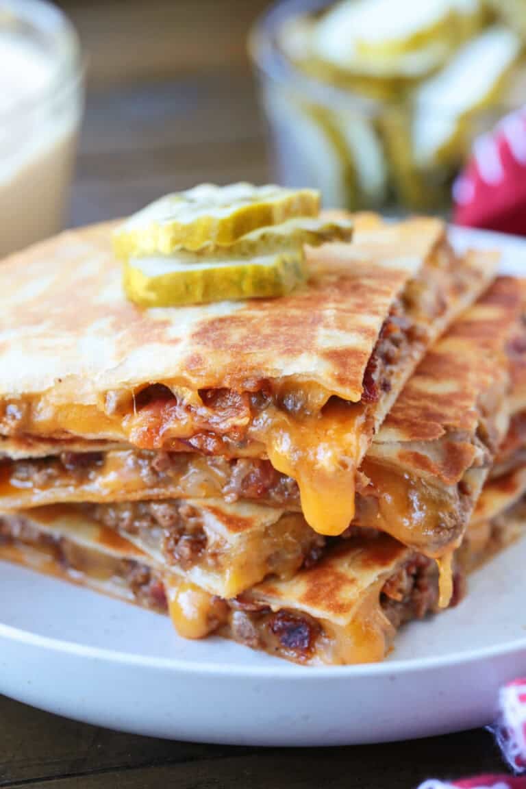 cheeseburger quesadillas stacked on a plate with cheese drip