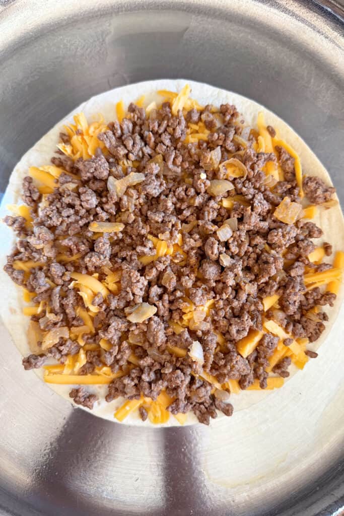open quesadilla with cheese and beef filling in skillet