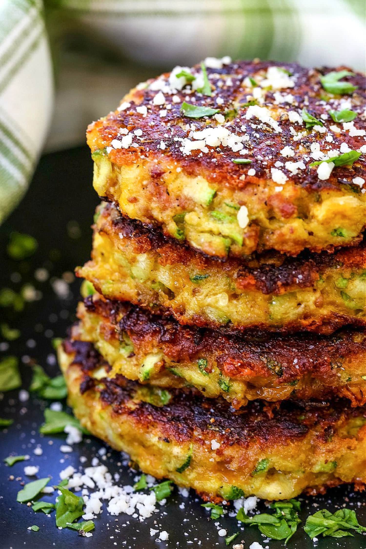 zucchini cakes stacked on black plate