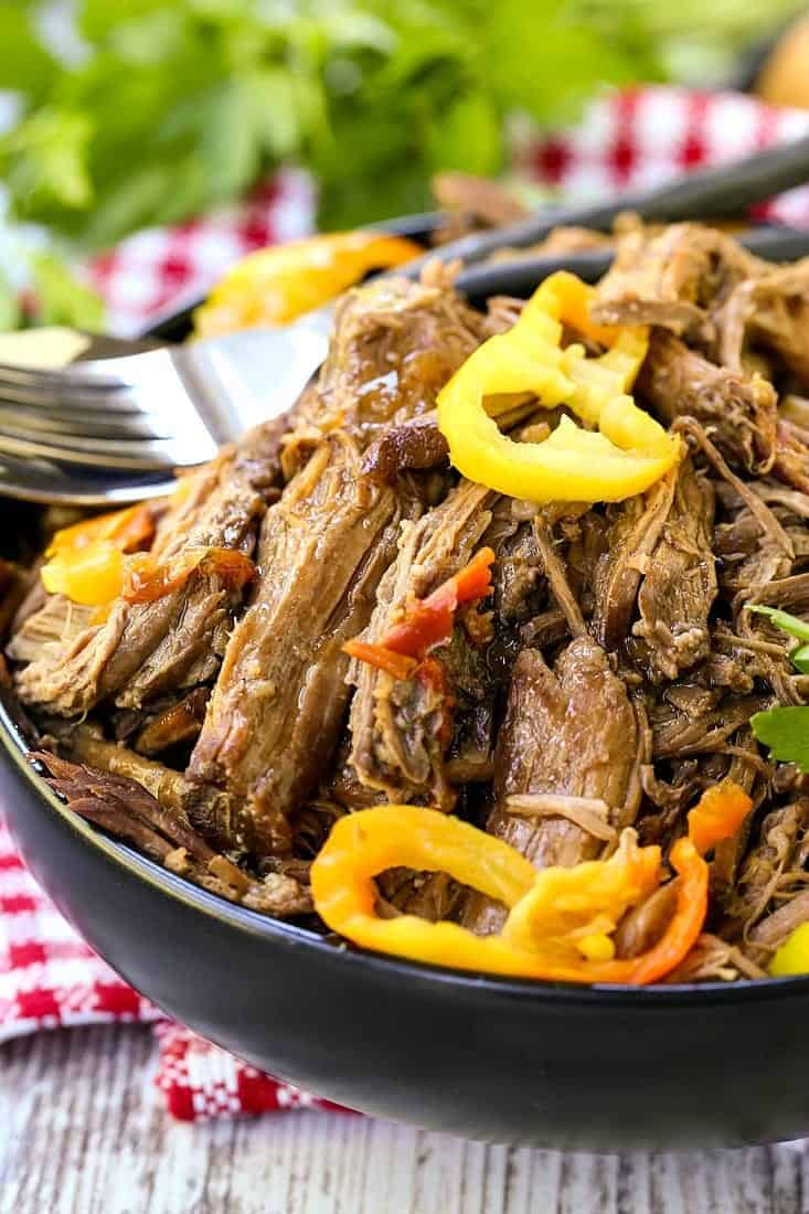 Pile this addicting Slow Cooker Italian Beef onto sub rolls, serve with mashed potatoes on the side or eat as is for a low carb meal! Slow cooker italian beef that's shredded in a black bowl