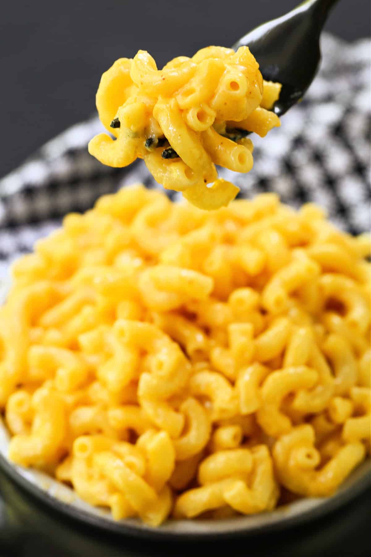 This 15-minute stovetop mac and cheese is creamy, cheesy, and packed with flavor! Skip the box and make this one-pot mac and cheese instead! fork full of macaroni and cheese over bowl