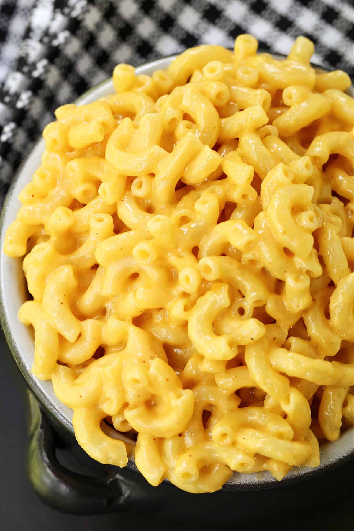 This 15-minute stovetop mac and cheese is creamy, cheesy, and packed with flavor! Skip the box and make this one-pot mac and cheese instead! black bowl of macaroni and cheese with checkered napkin