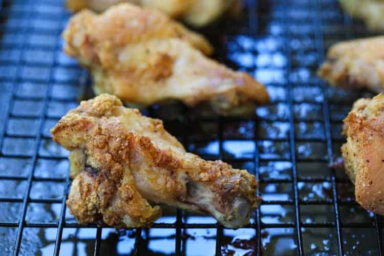 These Crispy Buffalo Chicken Wings are SO addicting and fall off the bone tender! A few tips make them as crispy as if you fried them! crispy chicken wings on a baking rack after cooking
