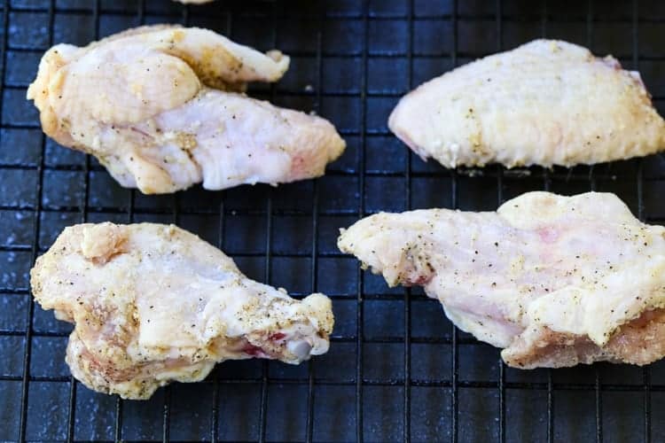 These Crispy Buffalo Chicken Wings are SO addicting and fall off the bone tender! A few tips make them as crispy as if you fried them! chicken wings on a baking rack
