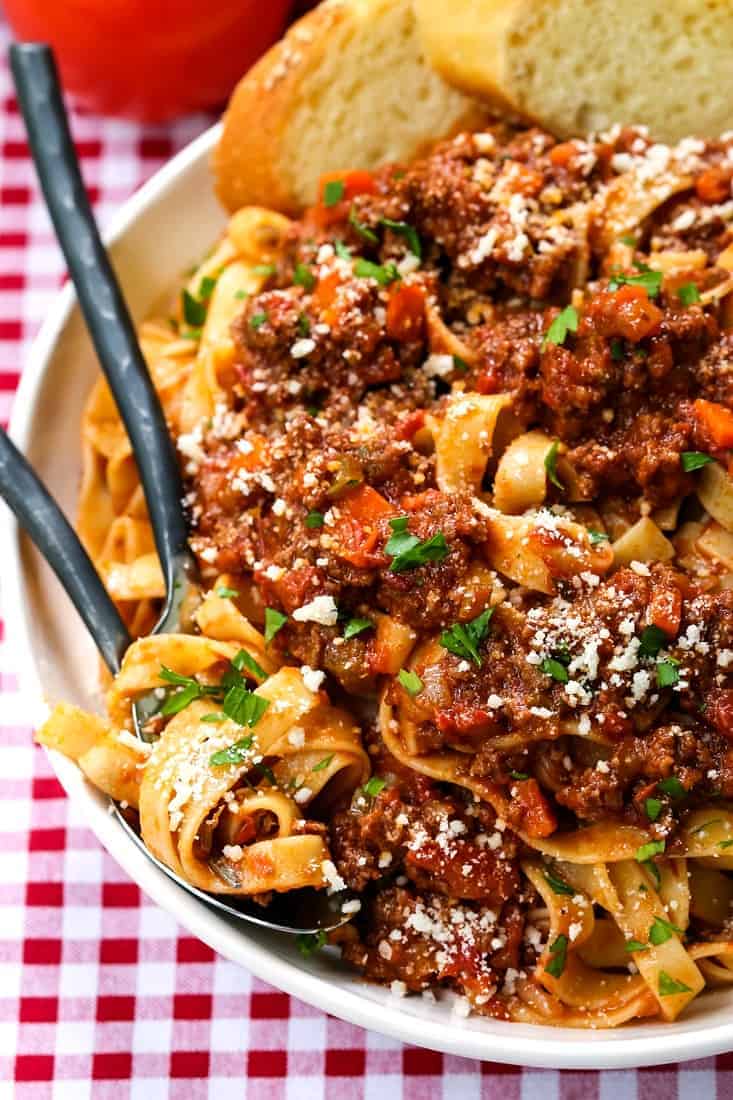 bolognese sauce in a white bowl with forks