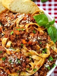 pasta with meat sauce in a white bowl with basil