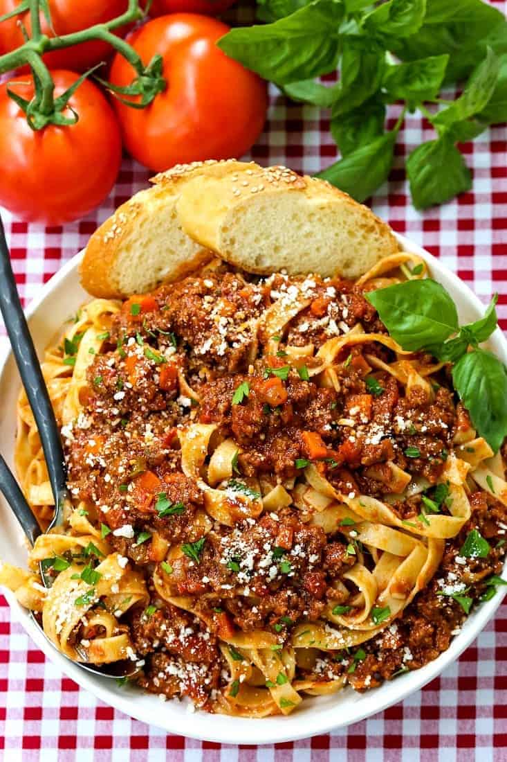 bolognese sauce over pasta on a red and white checkered tablecloth