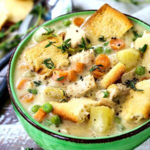 chicken pot pie soup in a green bowl with spoons