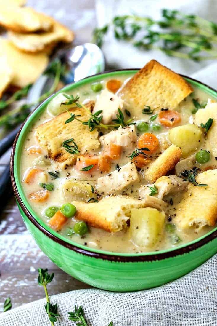 chicken pot pie soup in a green bowl with spoons