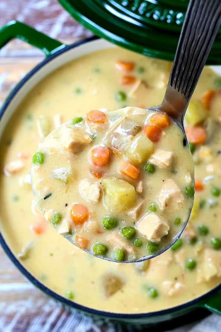 chicken pot pie soup in a ladle over a pot