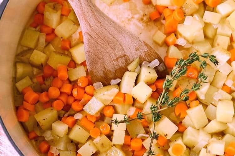 diced potato and carrot in a pot with thyme