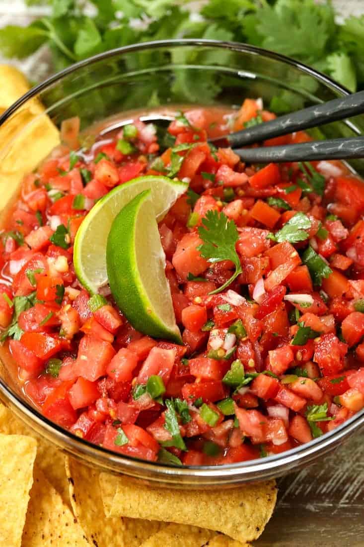 fresh pico de gallo in a bowl with limes