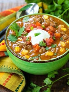 beefy taco soup in a green bowl with a colorful napkin