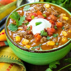 beefy taco soup in a green bowl with a colorful napkin