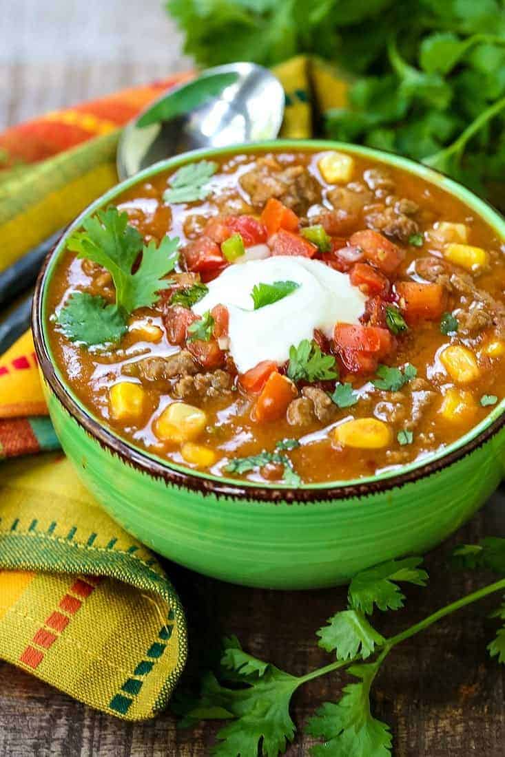 beefy taco soup in a green bowl with a colorful napkin