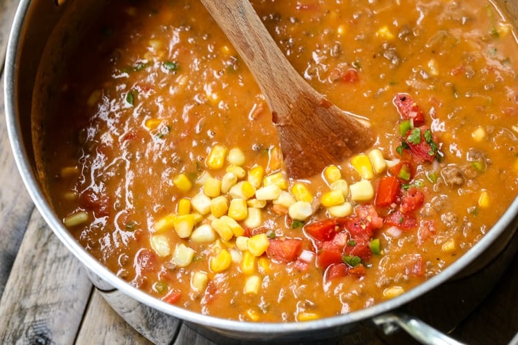taco soup cooking in a pot with a wooden spoon