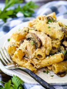 pasta with chicken and mushrooms on a white plate with a fork