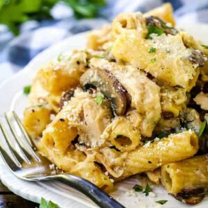 pasta with chicken and mushrooms on a white plate with a fork