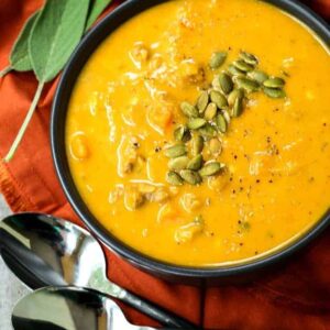 creamy pumpkin sausage soup in a black bowl with a rust colored napkin