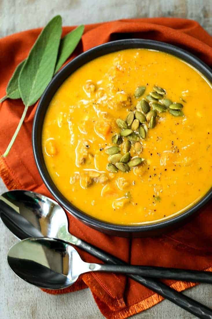 creamy pumpkin sausage soup in a black bowl with a rust colored napkin