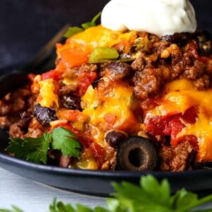 taco casserole on a black plate with sour cream