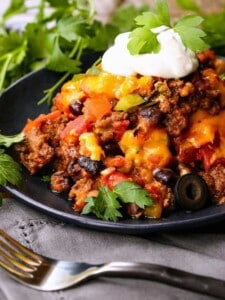 fiesta taco casserole on a black plate with cilantro