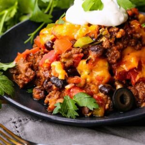 fiesta taco casserole on a black plate with cilantro