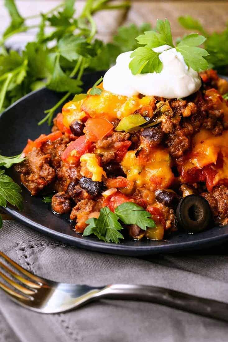 fiesta taco casserole on a black plate with cilantro