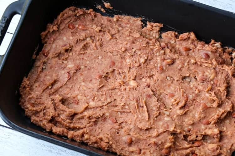 black casserole dish with refried beans on the bottom