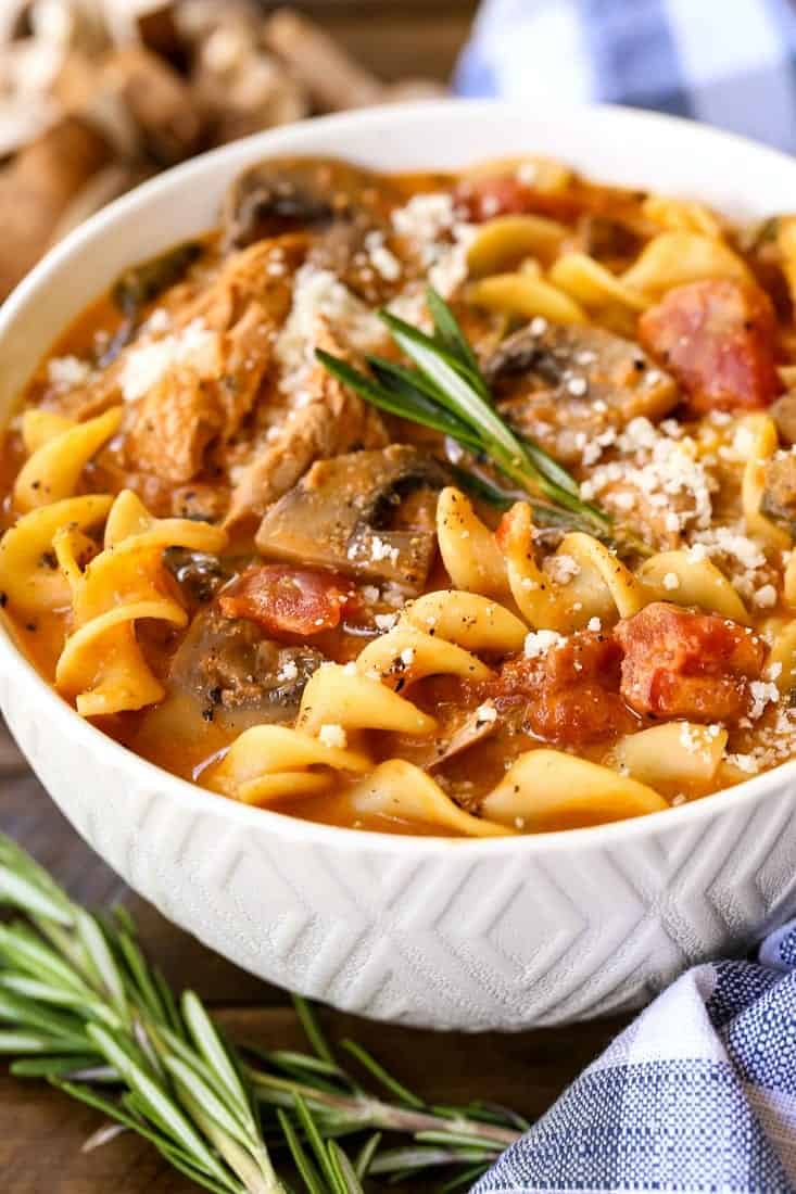 Chicken cacciatore soup in a white bowl with parmesan cheese