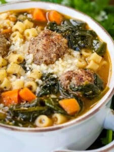 soup in a white crock with meatballs, pasta and spinach
