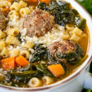 soup in a white crock with meatballs, pasta and spinach