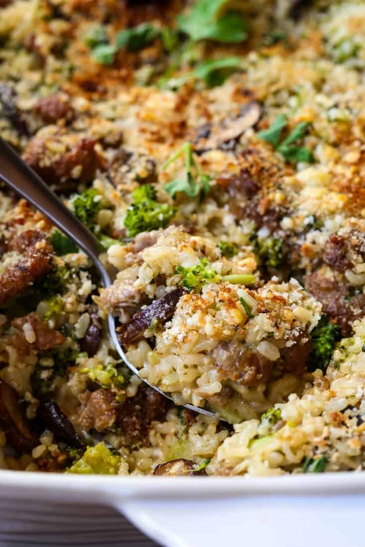 spoon of sausage and broccoli casserole in dish