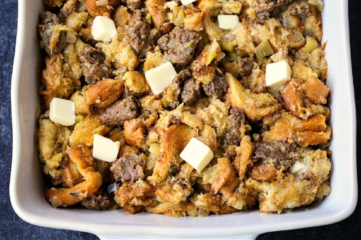uncooked stuffing in a casserole dish dotted with butter