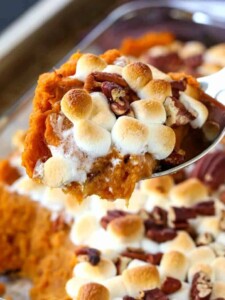 sweet potato casserole with marhmallows being spooned out of a casserole