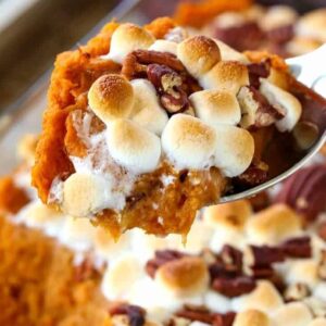 sweet potato casserole with marhmallows being spooned out of a casserole