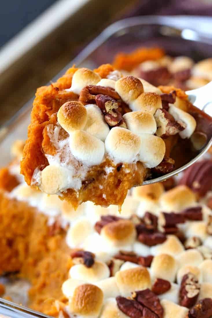 sweet potato casserole with marhmallows being spooned out of a casserole