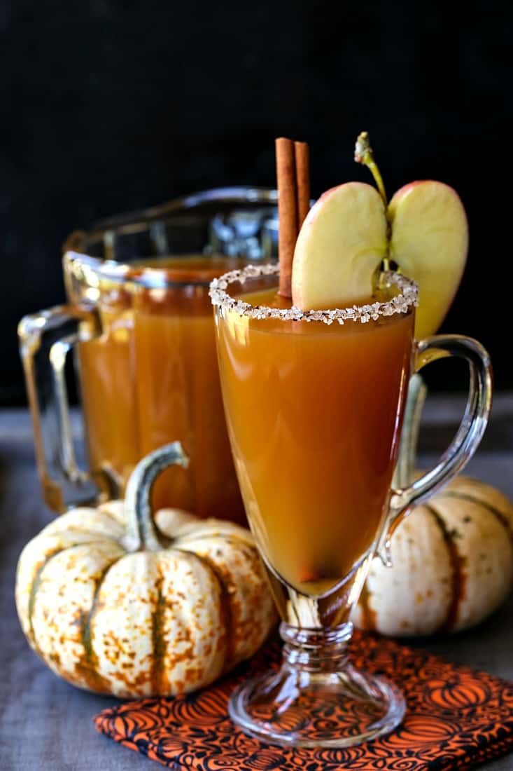 These Easy Thanksgiving Cocktails are going to be perfect for your Thanksgiving gathering! There's a drink recipe on here for everyone! slow cooker spiked cider cocktail with pumpkins in the background