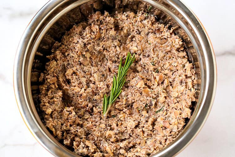 Creamy mushroom duxelle in a bowl with a sprig of rosemary.