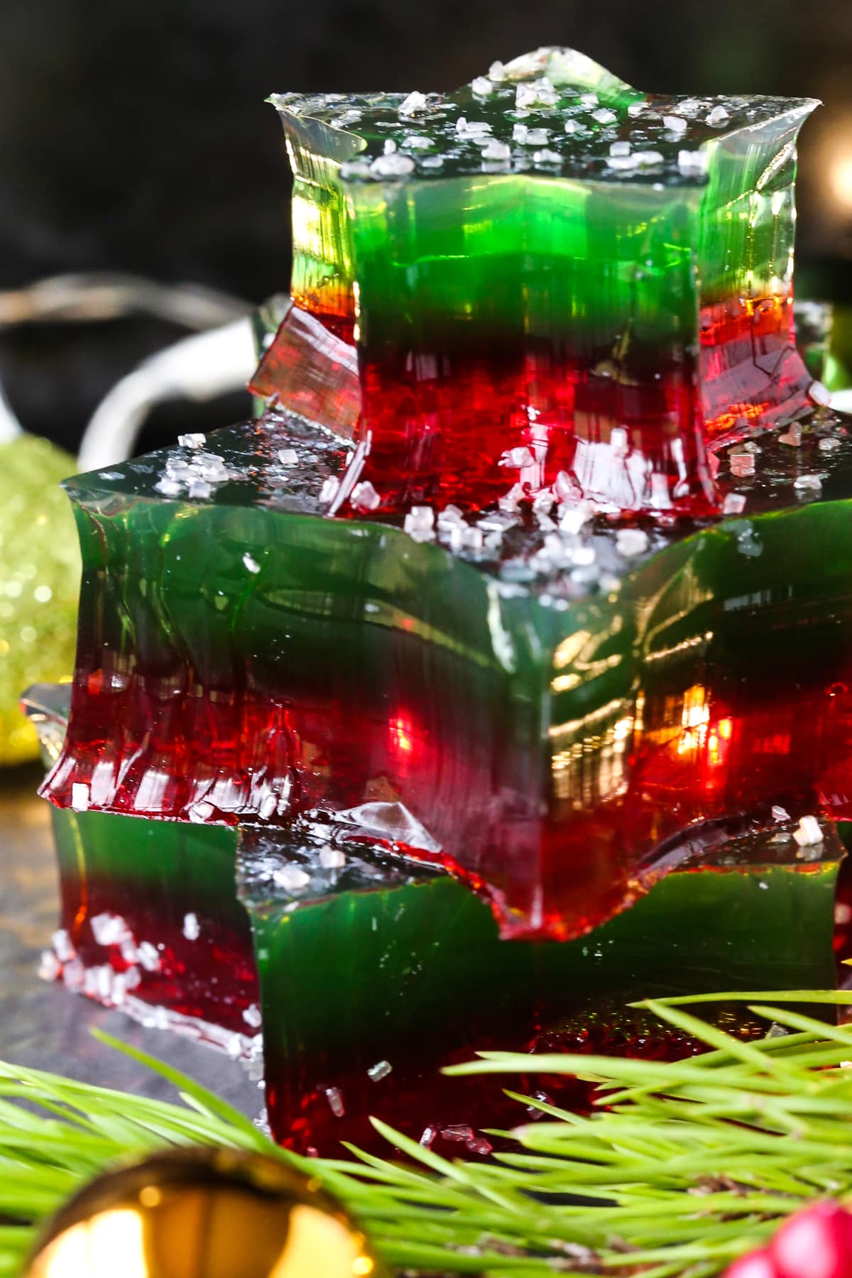 This Christmas Jello Dessert is going to be the star of the party! This festive dessert is made with a splash of real bubbly champagne! jello stars stacked on top of each other decorated for christmas