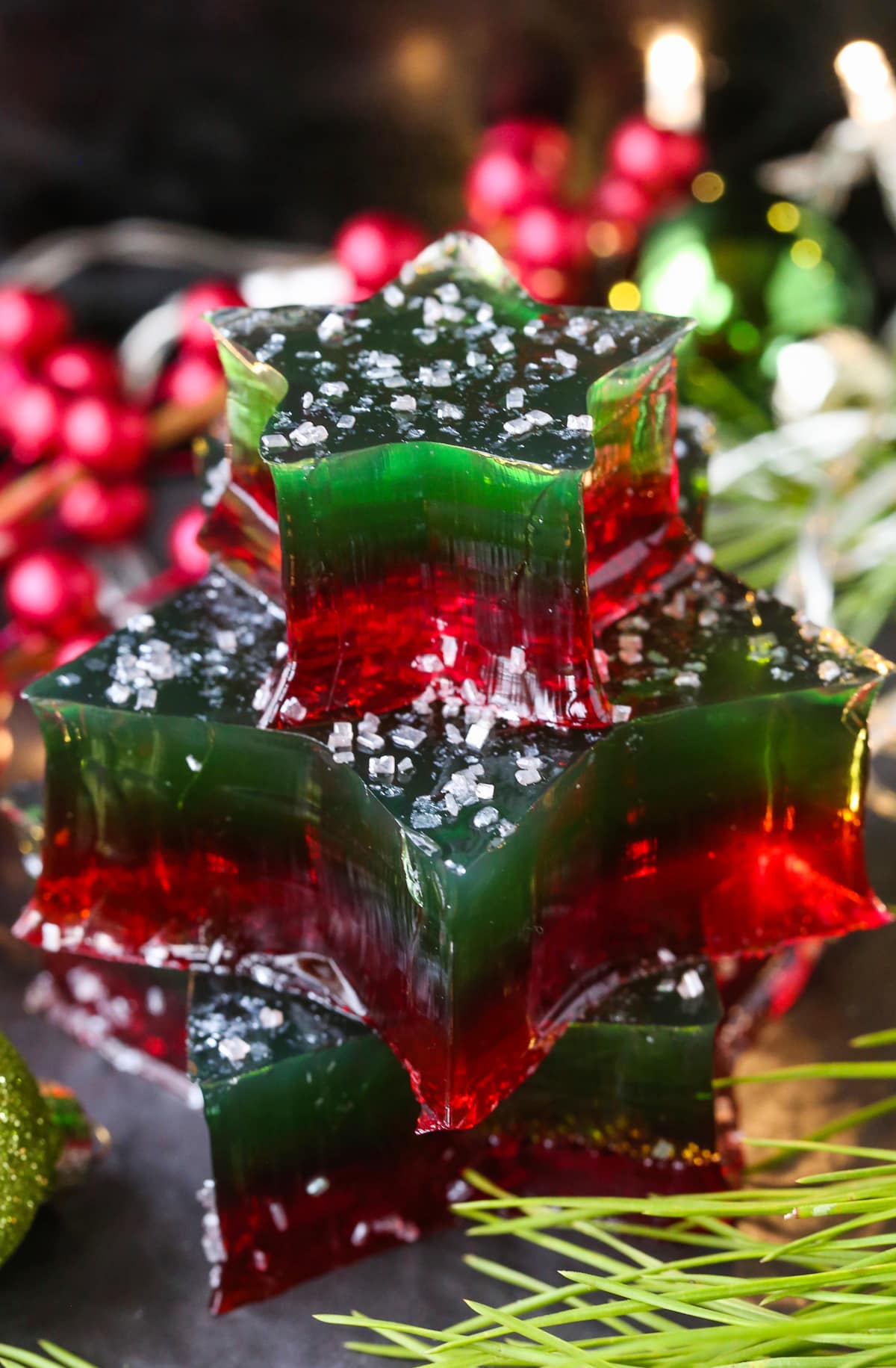 This Christmas Jello Dessert is going to be the star of the party! This festive dessert is made with a splash of real bubbly champagne! stacked jello stars decorated with christmas decorations